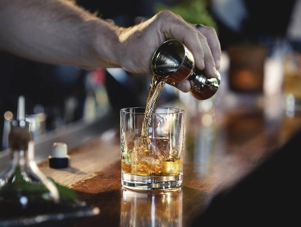 A hand pouring whiskey into a glass